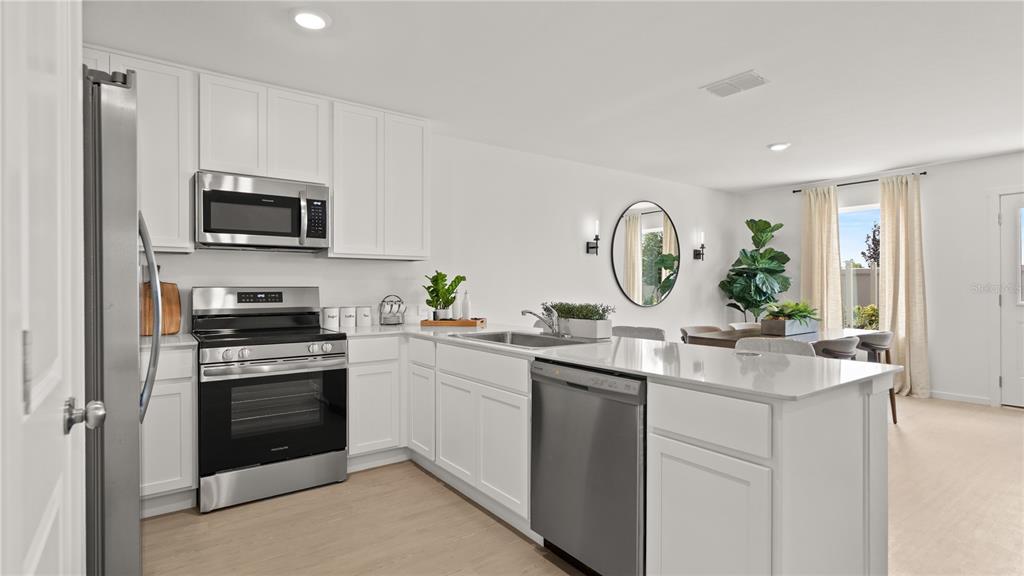 A modern kitchen features white cabinets, stainless steel appliances, and a quartz-topped island — 463 ARTEMIS STREET, LAKE WALES, FL