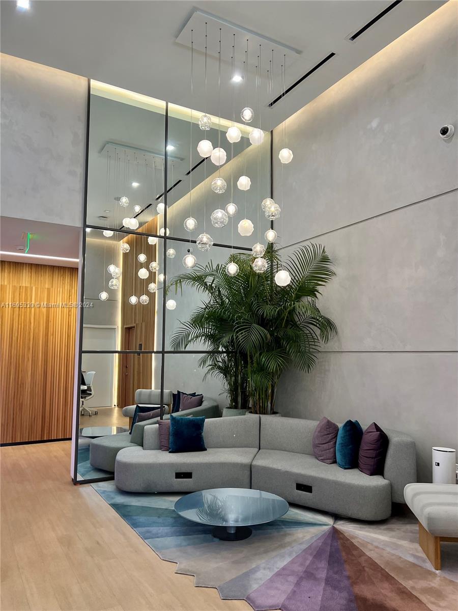 A modern lobby features a large mirror, a curved gray sofa, and a cascading globe chandelier — 227 NE 2nd St # 2613, Miami FL 33132, MIAMI, FL