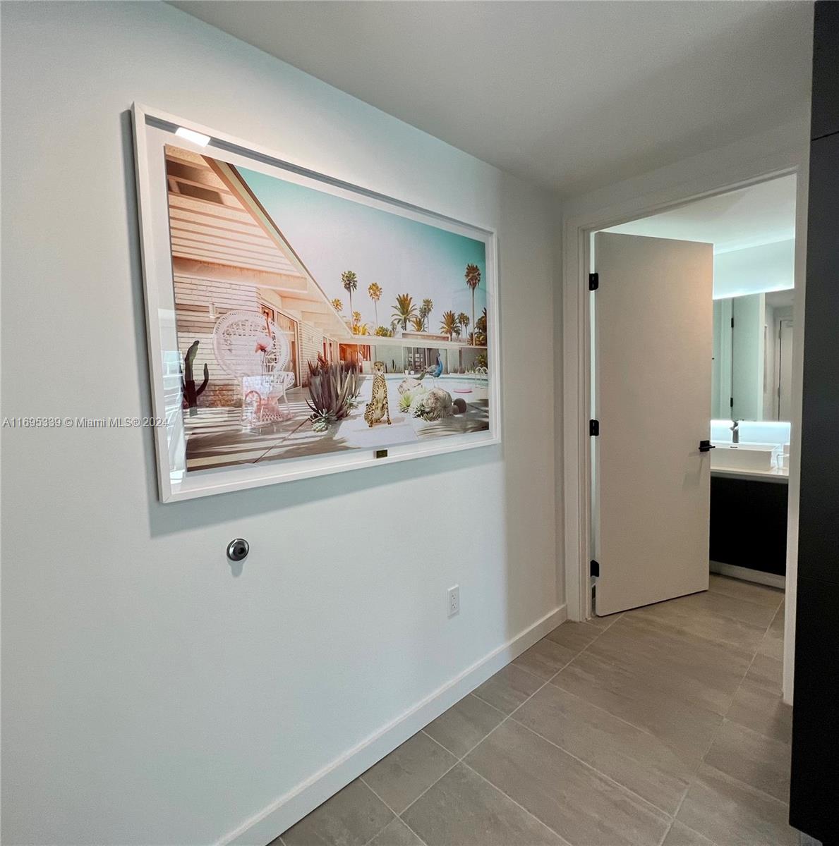 A framed photograph of a desert home hangs on a wall beside an open bathroom — 227 NE 2nd St # 2613, Miami FL 33132, MIAMI, FL