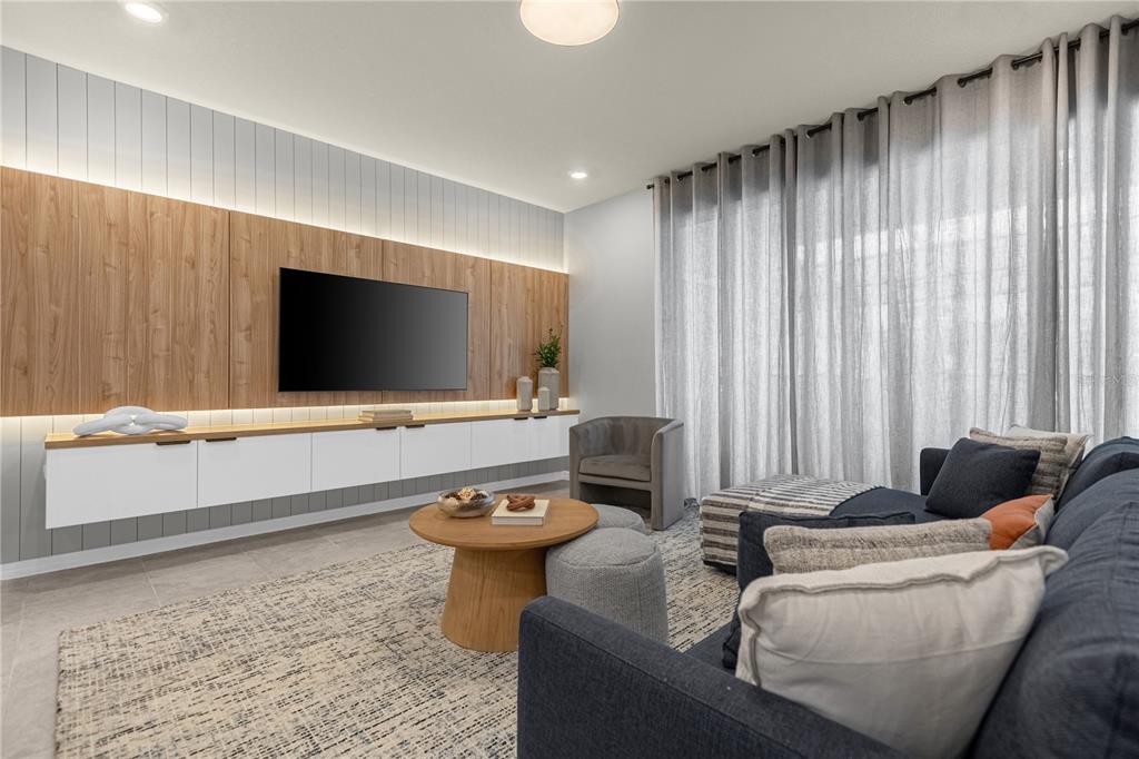 A living room features a wall-mounted television, wood paneling, white cabinetry, and a dark sofa — 4358 LANA AVENUE, DAVENPORT, FL