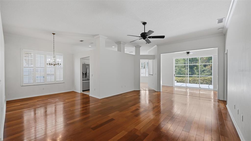 An open-concept living area features hardwood floors, a ceiling fan, and a screened-in patio view — 238 VESTAVIA DRIVE, VENICE, FL