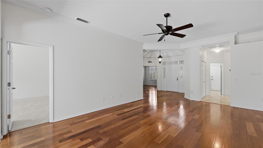 An empty living room features hardwood flooring, a ceiling fan, and white walls — 238 VESTAVIA DRIVE, VENICE, FL