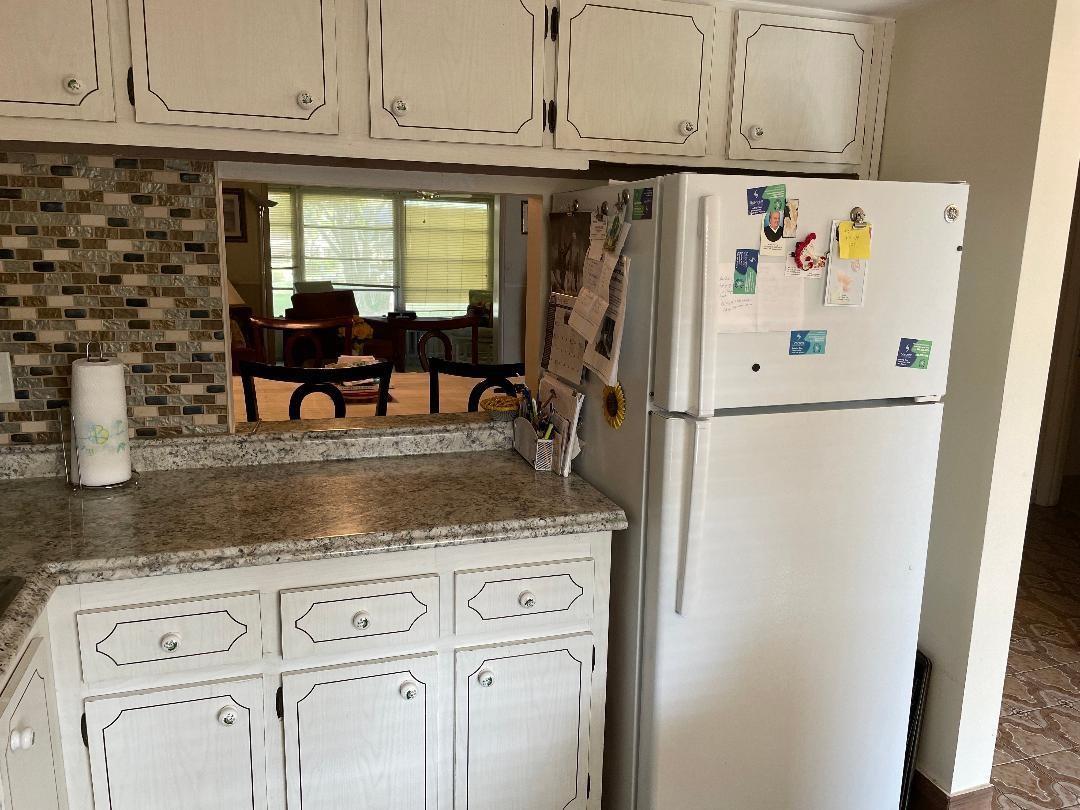A kitchen features white cabinets, granite countertops, a mosaic tile backsplash, and a white refrigerator — 7410 NW 1st Street # 202, Margate FL 33063, MARGATE, FL