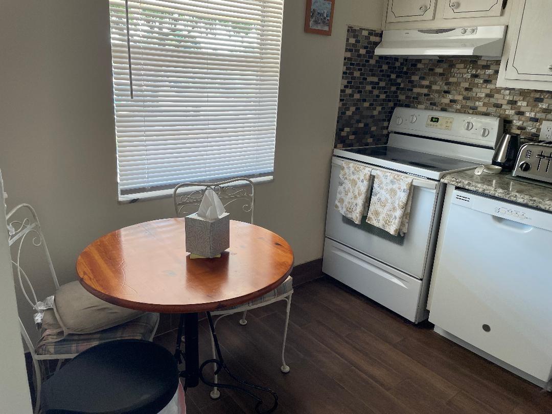A small kitchen features a round wooden dining table, white appliances, and a tiled backsplash — 7410 NW 1st Street # 202, Margate FL 33063, MARGATE, FL