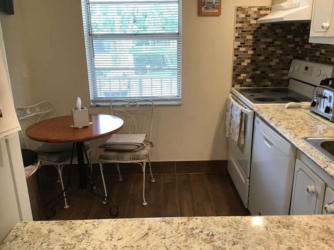 A small kitchen features a round wooden table, white appliances, and granite countertops — 7410 NW 1st Street # 202, Margate FL 33063, MARGATE, FL
