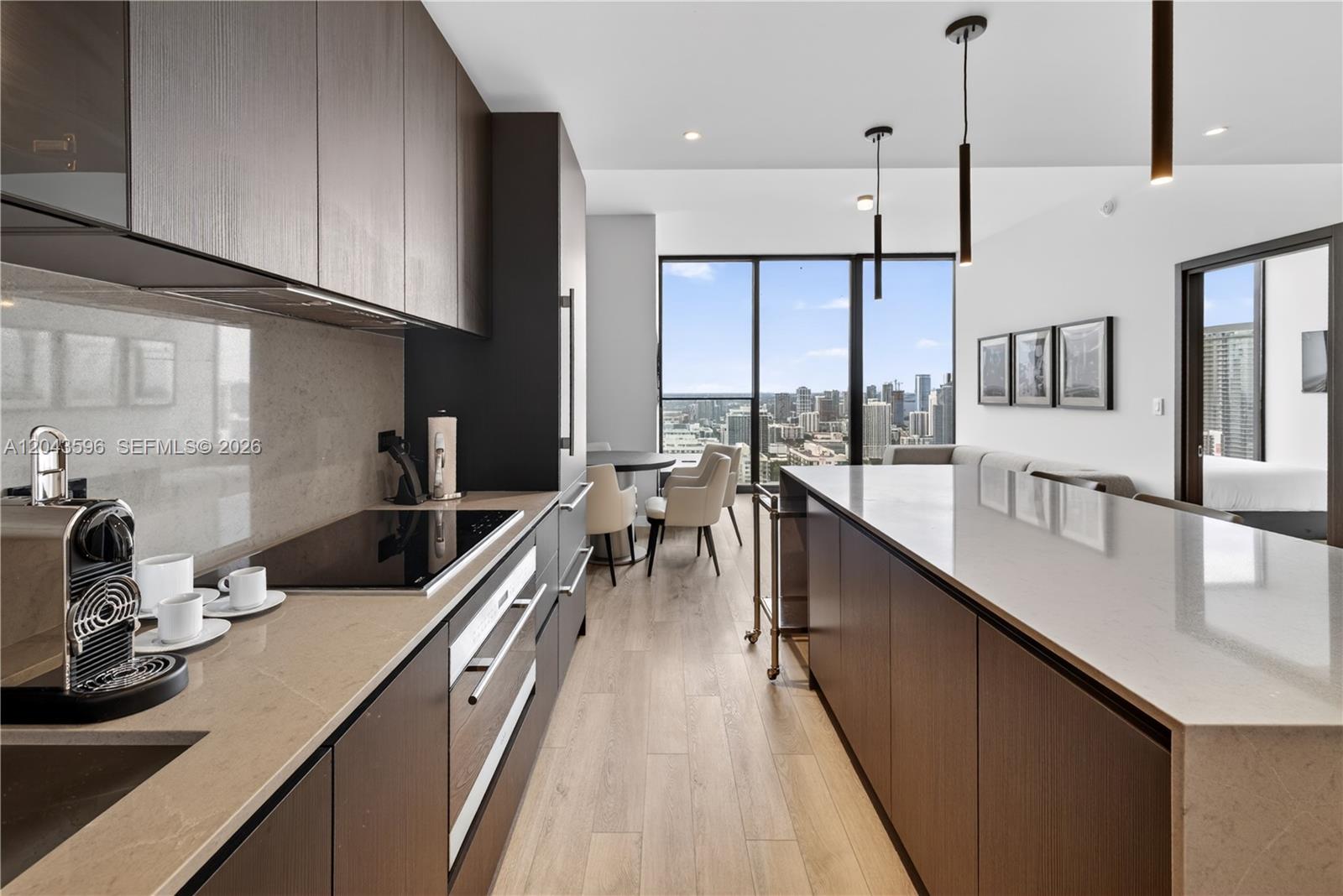 A modern kitchen features dark wood cabinetry, a stone island, and floor-to-ceiling city views — 20 NE 11th # 4702, Miami FL 33132, MIAMI, FL