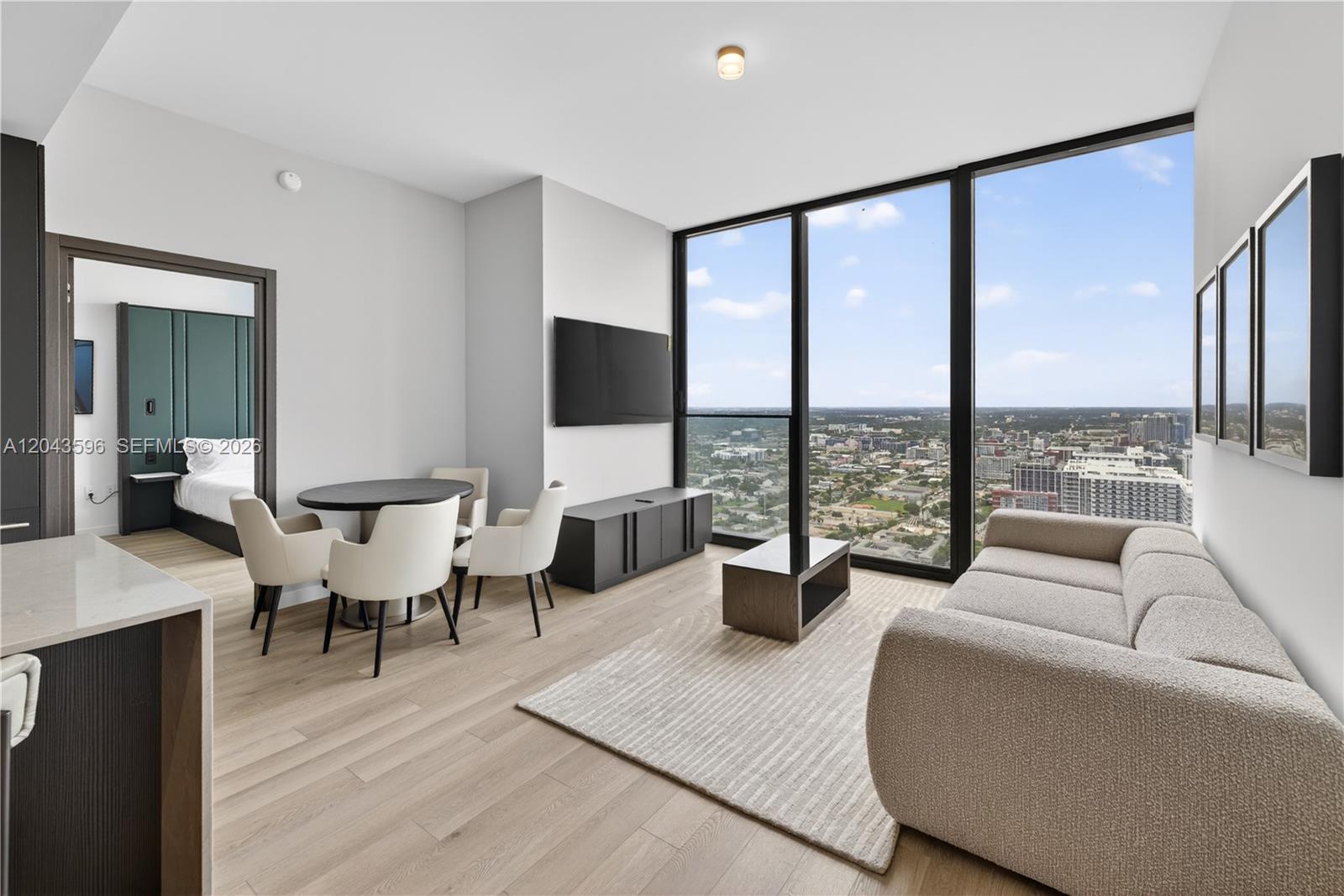 A modern living room with a dining area, floor-to-ceiling windows, and a city view — 20 NE 11th # 4702, Miami FL 33132, MIAMI, FL