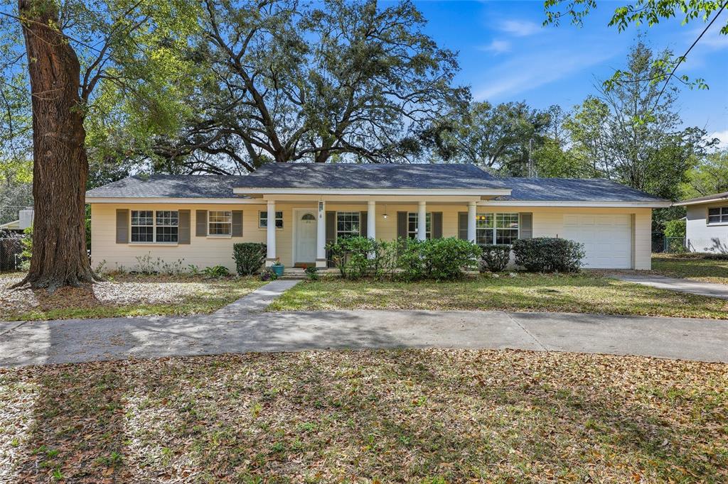 A single-story house with light yellow siding, a covered front porch, and a large tree — 812 NW 36TH TERRACE, GAINESVILLE, FL