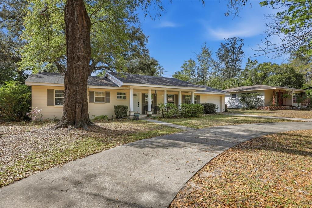 A single-story yellow house with a covered porch and a curved concrete driveway — 812 NW 36TH TERRACE, GAINESVILLE, FL