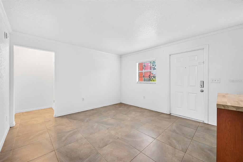 An empty room with white walls, tile flooring, a window, and a white entry door — 2423 E CENTRAL BOULEVARD UNIT 1, ORLANDO, FL