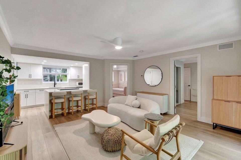 A living room with a curved sofa, wooden chair, and an open kitchen with bar seating — 49 SE 7th Avenue # 2, Delray Beach FL 33483, DELRAY BEACH, FL
