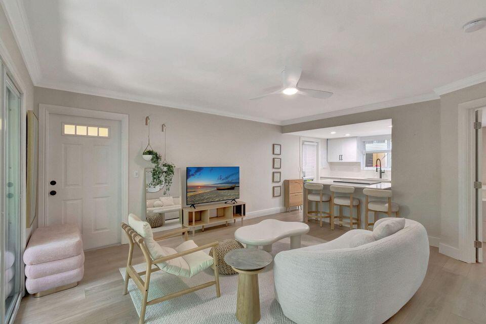 A bright living room features light wood flooring, a white sofa, and an open kitchen — 49 SE 7th Avenue # 2, Delray Beach FL 33483, DELRAY BEACH, FL
