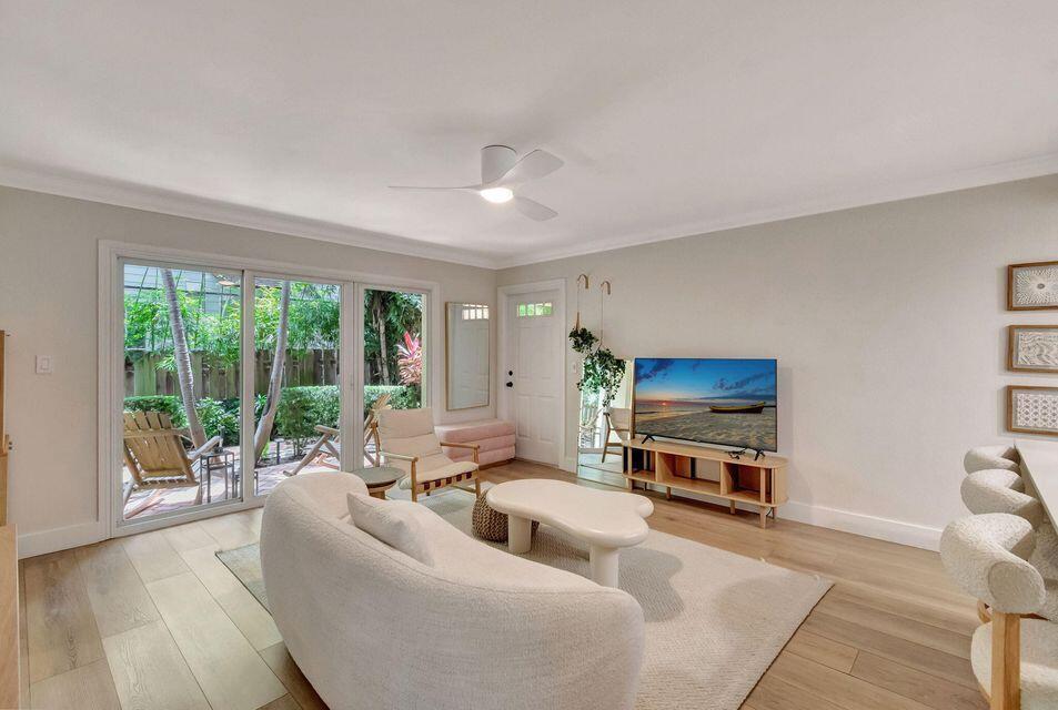 A living room features a curved white sofa, a coffee table, and sliding glass doors — 49 SE 7th Avenue # 2, Delray Beach FL 33483, DELRAY BEACH, FL