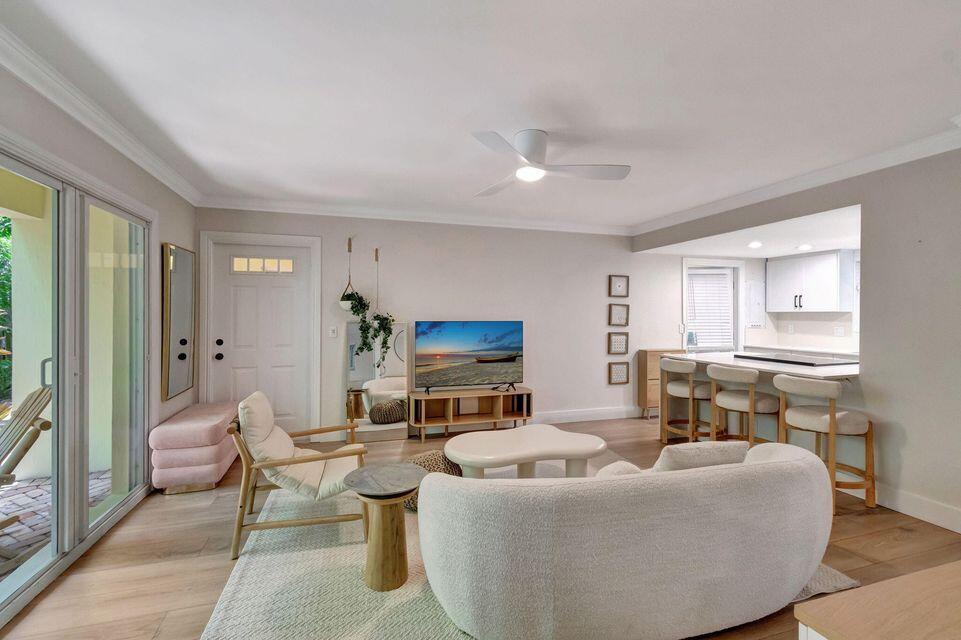 A living room features a curved sofa, a television, and a breakfast bar with stools — 49 SE 7th Avenue # 2, Delray Beach FL 33483, DELRAY BEACH, FL