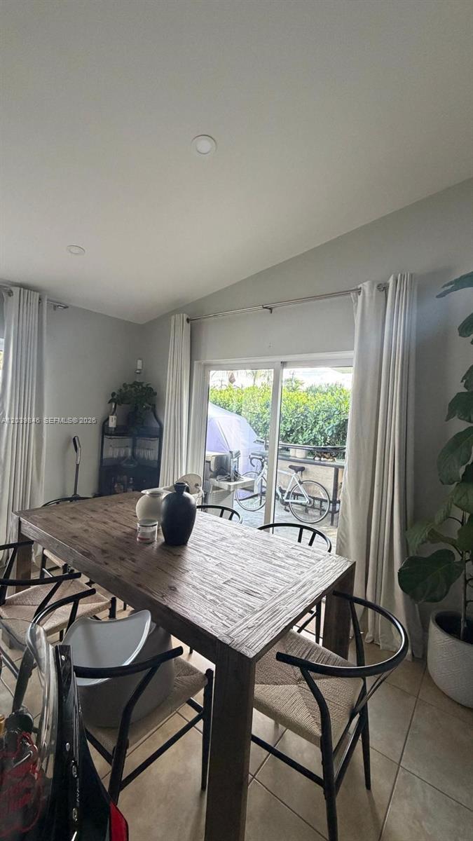A dining room features a wooden table, black chairs, and sliding glass doors to a patio — 8121 SW 136th Pl # 8121, Miami FL 33183, MIAMI, FL