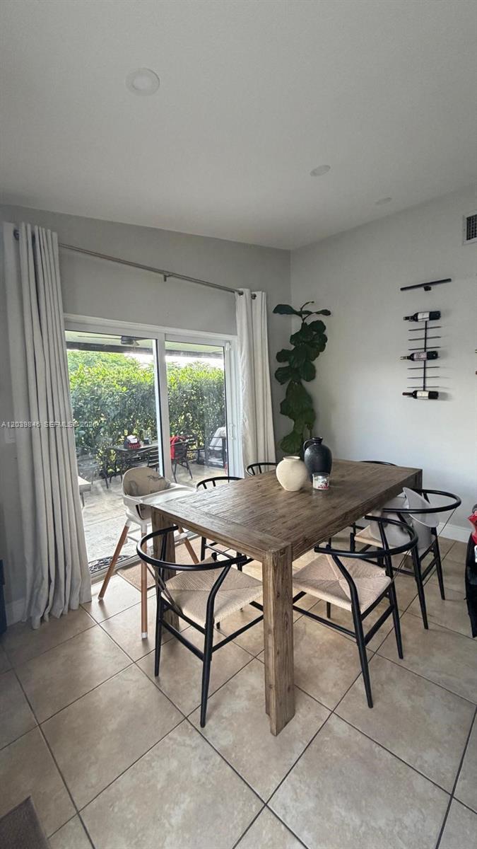 A dining room features a wooden table, black chairs, a wine rack, and sliding glass doors — 8121 SW 136th Pl # 8121, Miami FL 33183, MIAMI, FL