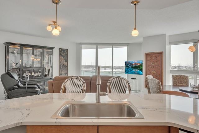 A kitchen island with a sink overlooks a living area with a view of a bridge — 231 RIVERSIDE DRIVE UNIT 709-1, DAYTONA BEACH, FL