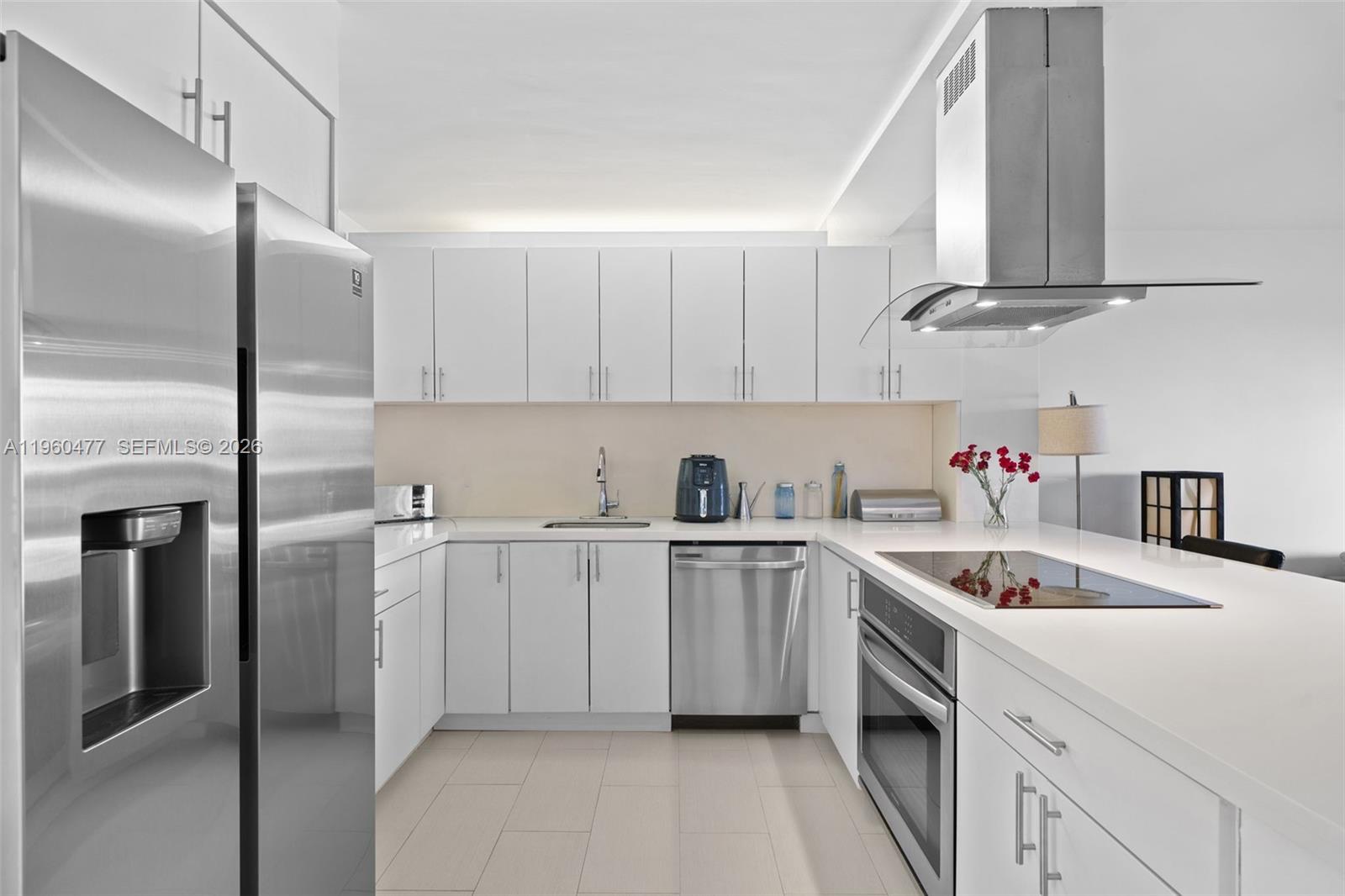 A modern kitchen features white cabinetry, stainless steel appliances, and white countertops — 240 Galen Drive # 109, Key Biscayne FL 33149, KEY BISCAYNE, FL