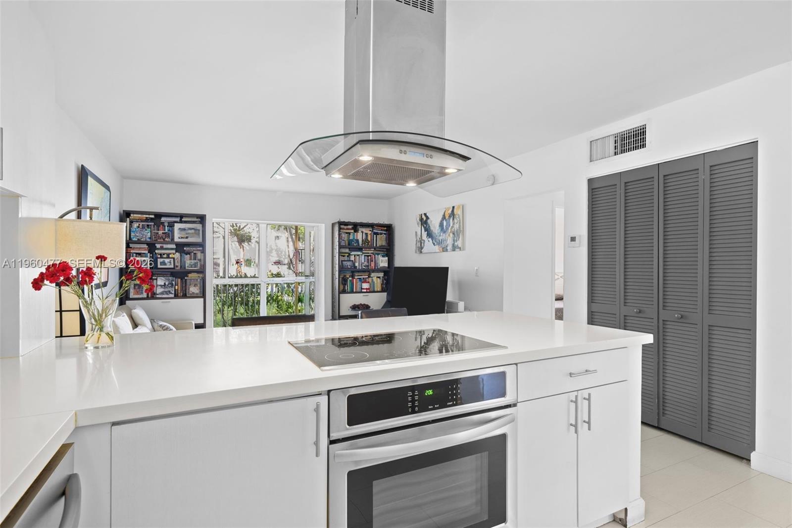 A modern kitchen features a white island with a cooktop, oven, and stainless steel hood — 240 Galen Drive # 109, Key Biscayne FL 33149, KEY BISCAYNE, FL