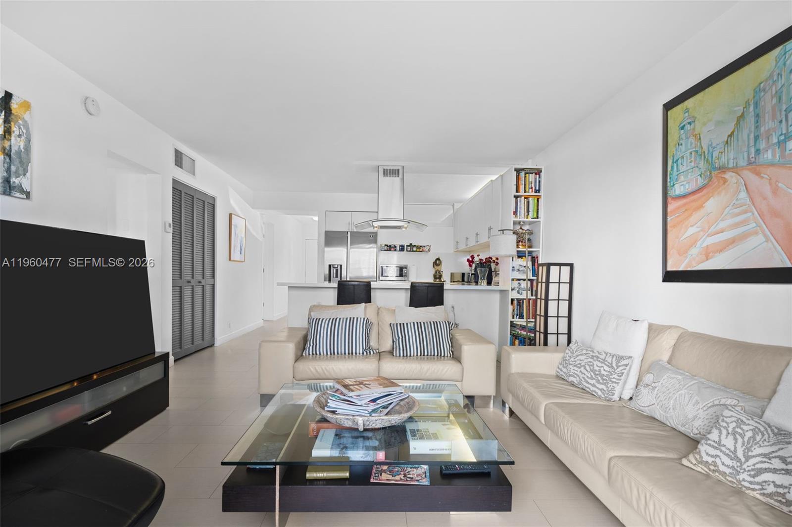 A living room features a beige sofa, glass coffee table, and an open-concept kitchen — 240 Galen Drive # 109, Key Biscayne FL 33149, KEY BISCAYNE, FL