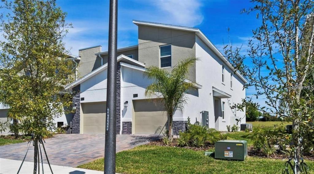 A two-story duplex with a paved driveway, two garage doors, and light-colored stucco siding — 857 OCEAN COURSE AVENUE UNIT 857, DAVENPORT, FL