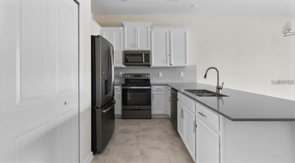 A kitchen features white cabinets, dark gray countertops, and stainless steel appliances — 857 OCEAN COURSE AVENUE UNIT 857, DAVENPORT, FL