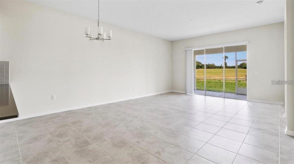 An empty dining area features light tile flooring, a chandelier, and sliding glass patio doors — 857 OCEAN COURSE AVENUE UNIT 857, DAVENPORT, FL