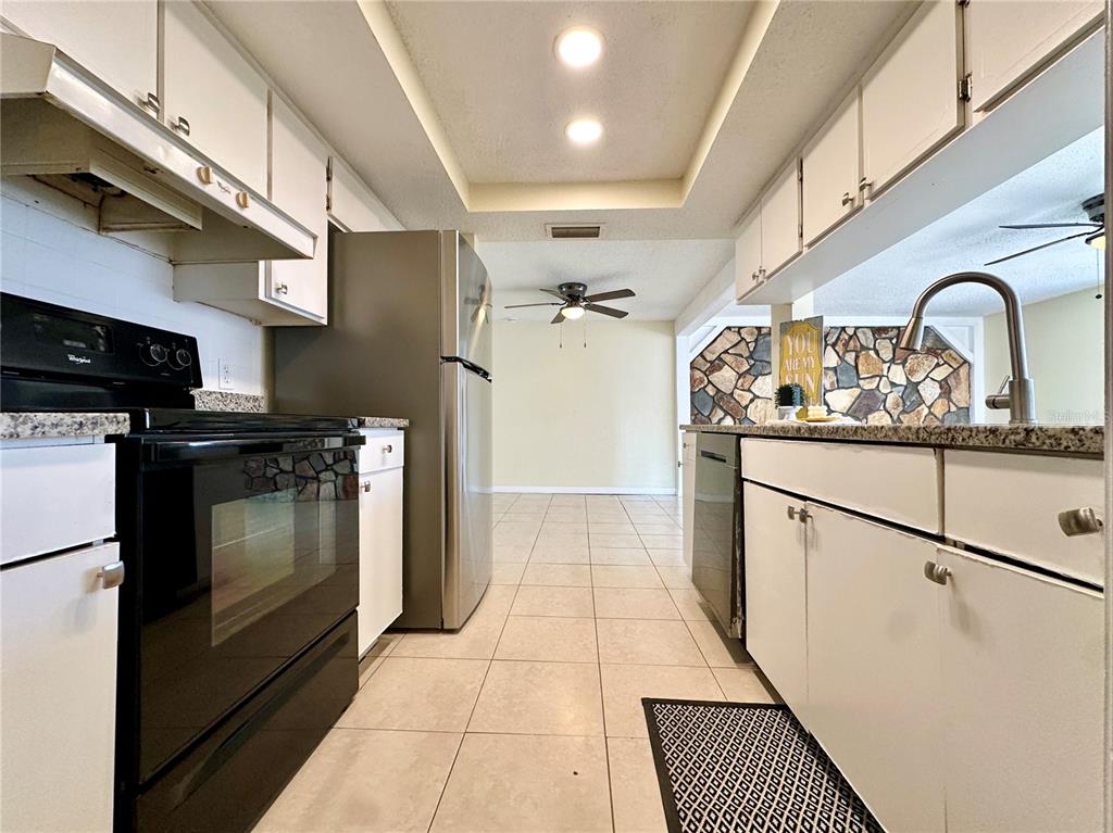 A kitchen with white cabinets, stainless steel appliances, and a stone accent wall — 5054 SCHOOL ROAD, NEW PORT RICHEY, FL