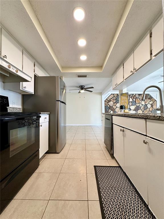 A galley kitchen features white cabinets, stainless steel appliances, and tile flooring — 5054 SCHOOL ROAD, NEW PORT RICHEY, FL