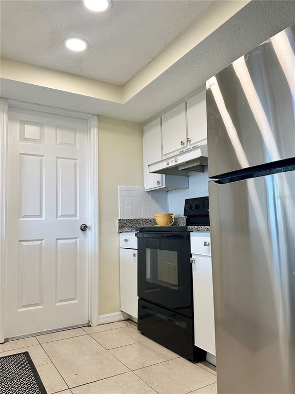 A kitchen features white cabinets, a black stove, granite countertops, and a stainless steel refrigerator — 5054 SCHOOL ROAD, NEW PORT RICHEY, FL
