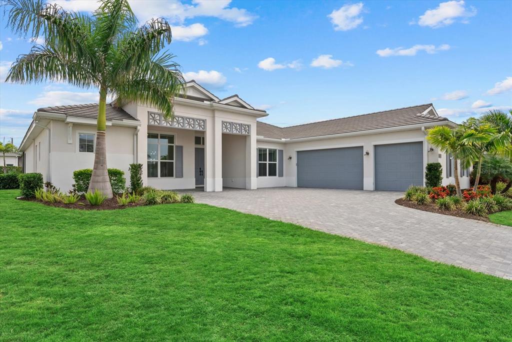 A single-story house with a paved driveway, three-car garage, and a prominent palm tree — 8133 NEVIS RUN, BRADENTON, FL