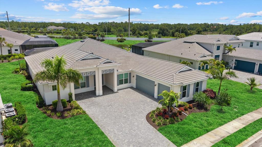 An aerial view of a suburban house with a paved driveway and a tiled roof — 8133 NEVIS RUN, BRADENTON, FL