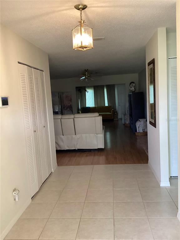 A tiled entryway leads into a living room with wood flooring and a white sofa — 2512 LANCASTER DRIVE UNIT 2512, SUN CITY CENTER, FL