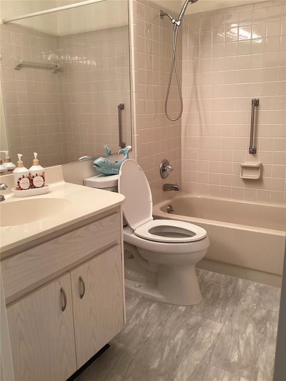 A bathroom features a vanity, a toilet, and a tiled shower-tub combination — 2512 LANCASTER DRIVE UNIT 2512, SUN CITY CENTER, FL