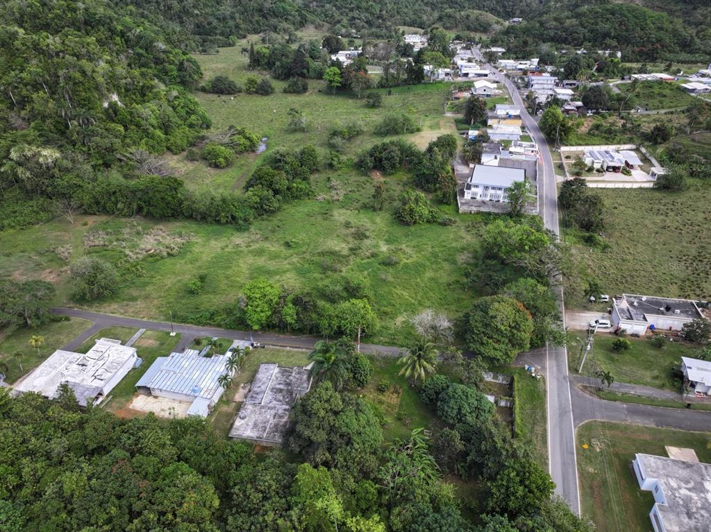 An aerial view shows a rural landscape with houses, a paved road, and green fields — CARR 448, CAMUY, PR