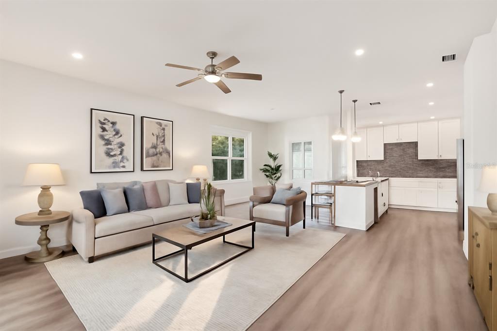 A bright open-concept living room and kitchen with light wood floors and white cabinetry — 1885 9TH AVENUE, DELAND, FL