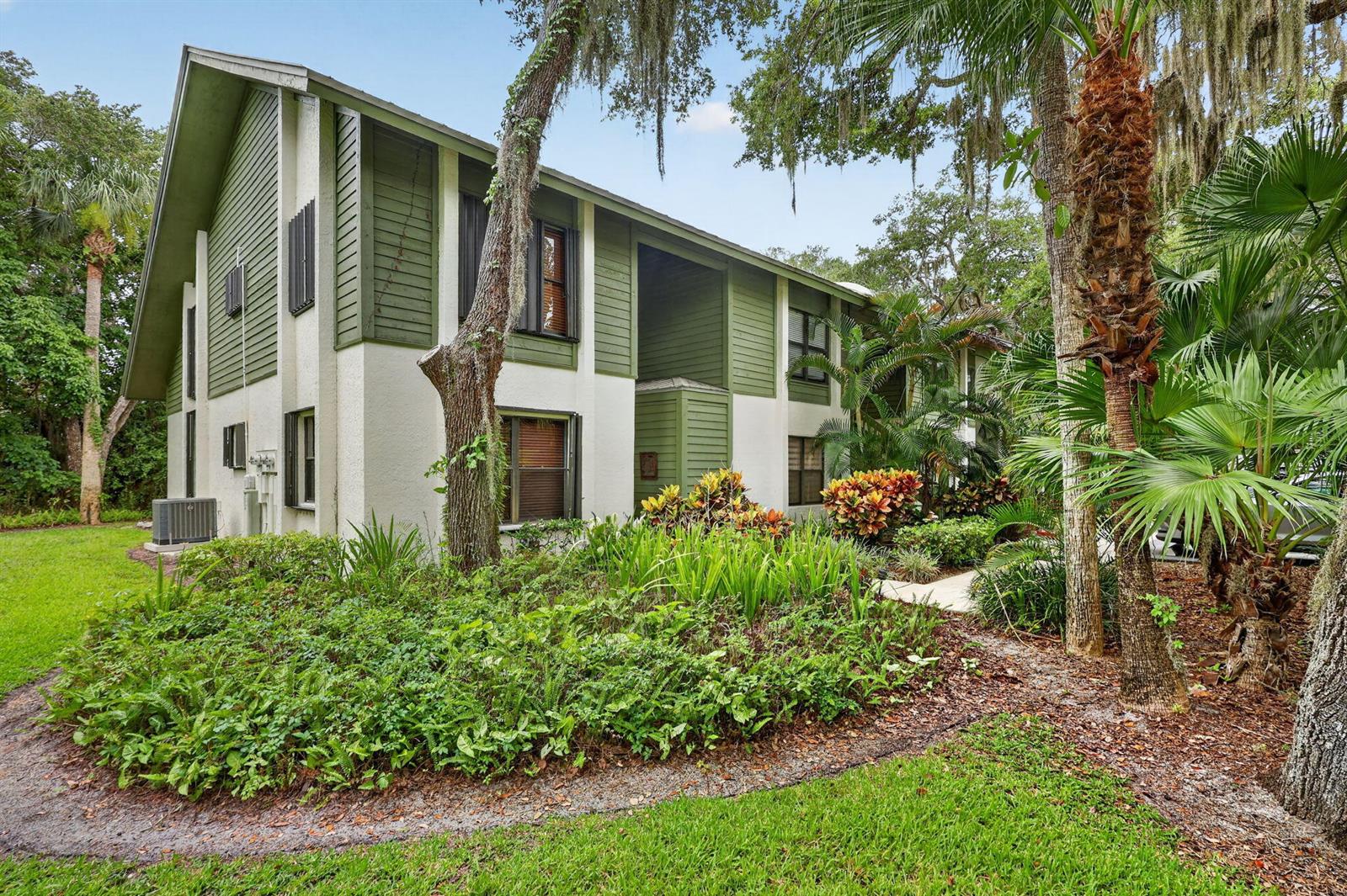 A two-story apartment building with green and white siding surrounded by lush tropical landscaping — 5250 SE Seascape Way # 102, Stuart FL 34997, STUART, FL