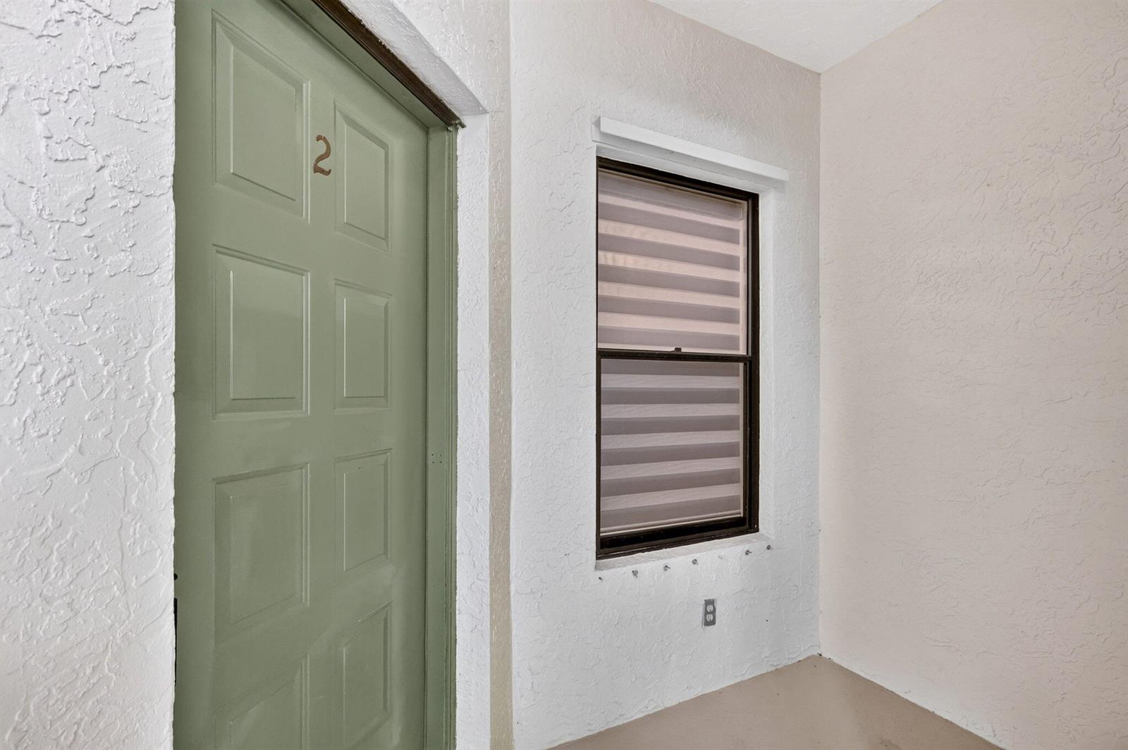 A green door marked with the number two sits beside a window on a porch — 5250 SE Seascape Way # 102, Stuart FL 34997, STUART, FL
