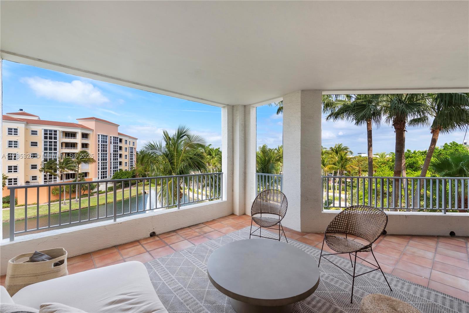 A covered balcony features tiled flooring, two chairs, a round table, and a water view — 705 Crandon Blvd # 405, Key Biscayne FL 33149, KEY BISCAYNE, FL