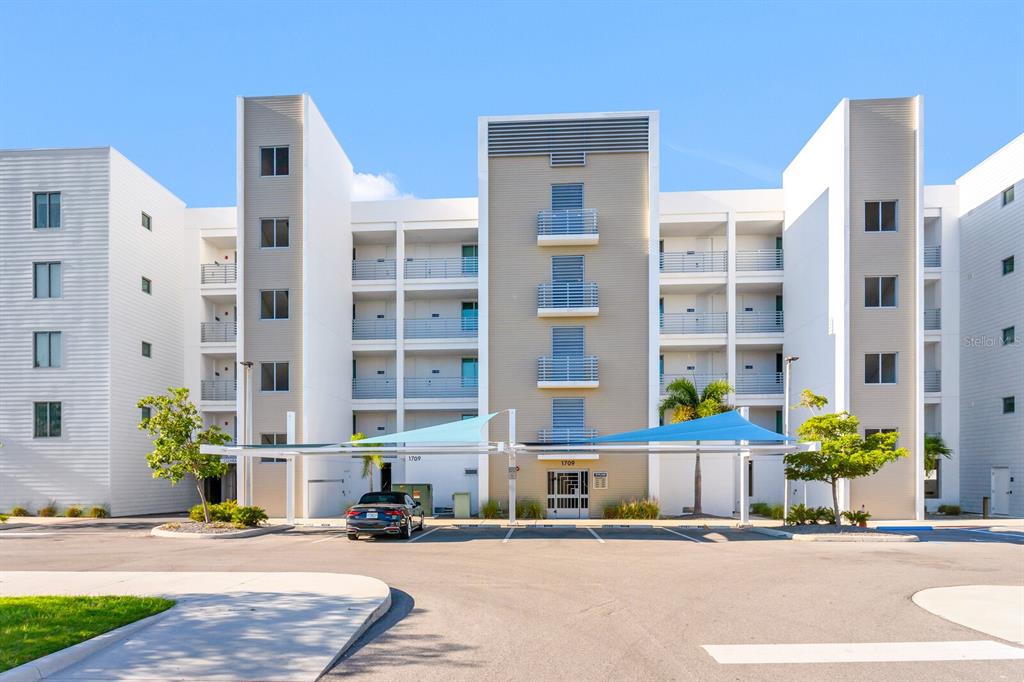 A modern multi-story apartment building with covered parking and a central entrance under a canopy — 1709 N TAMIAMI TRAIL UNIT 503, SARASOTA, FL