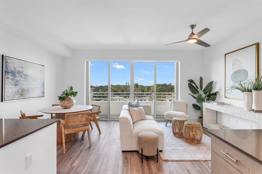 A bright living and dining area features wood-look flooring, a balcony, and modern neutral furniture — 1709 N TAMIAMI TRAIL UNIT 503, SARASOTA, FL