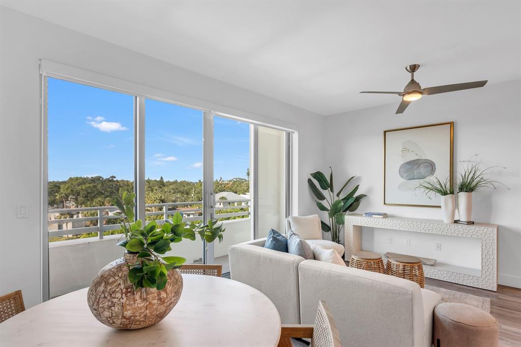 A bright living room features a white sofa, a dining table, and a balcony view — 1709 N TAMIAMI TRAIL UNIT 503, SARASOTA, FL