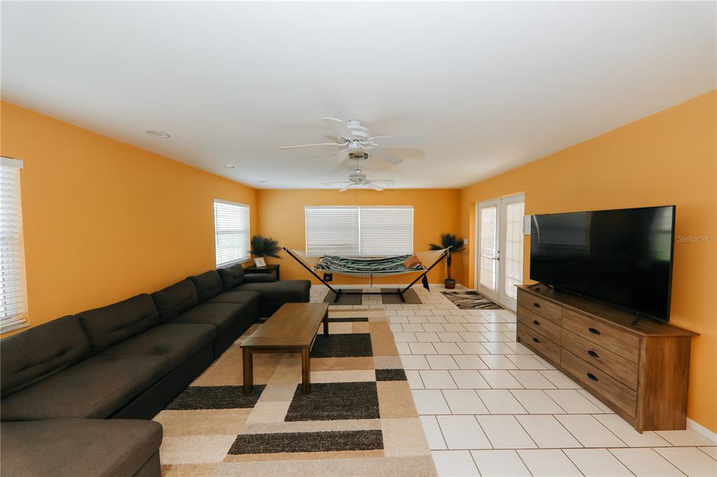 A living room features orange walls, tile flooring, a large sectional sofa, and a hammock — 5211 24TH AVENUE DRIVE W, BRADENTON, FL