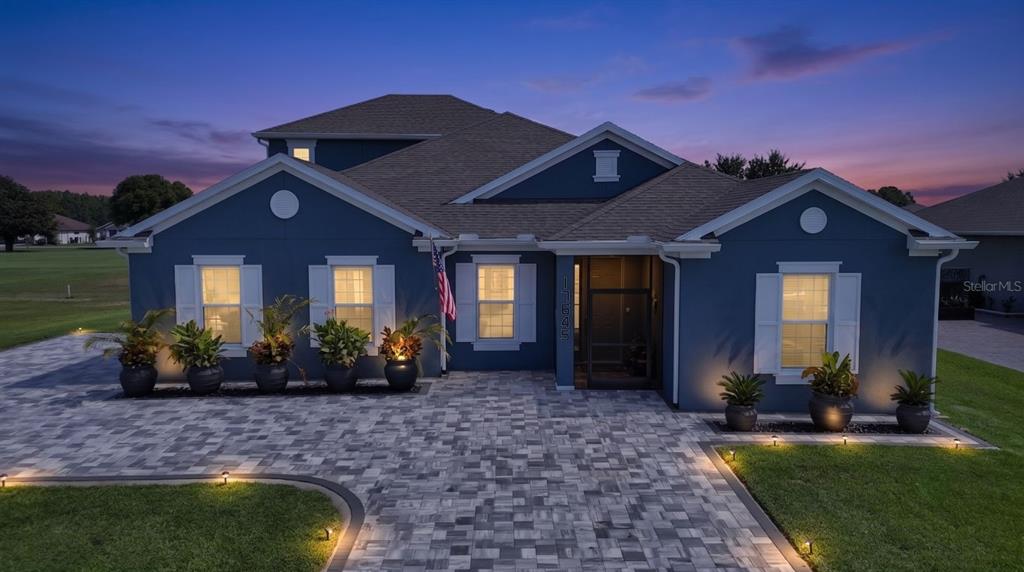 A blue house with a paved driveway and landscaped planters at dusk — 17649 LIVE OAK DRIVE, TAVARES, FL