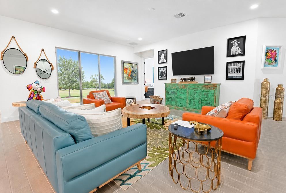 A living room features a blue sofa, orange armchairs, a wood coffee table, and green console — 17649 LIVE OAK DRIVE, TAVARES, FL