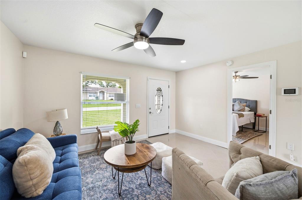 A living room features a blue sofa, a round wooden coffee table, and a ceiling fan — 5225 DEERFIELD AVENUE, SPRING HILL, FL