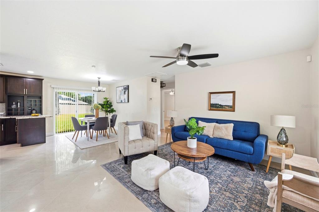 A living room and dining area feature a blue sofa, neutral furniture, and tile flooring — 5225 DEERFIELD AVENUE, SPRING HILL, FL