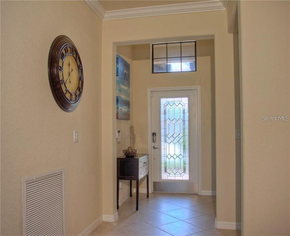 A foyer with tile flooring, a decorative wall clock, and a glass-paneled front door — 218 WHISPERING PALMS LANE, BRADENTON, FL