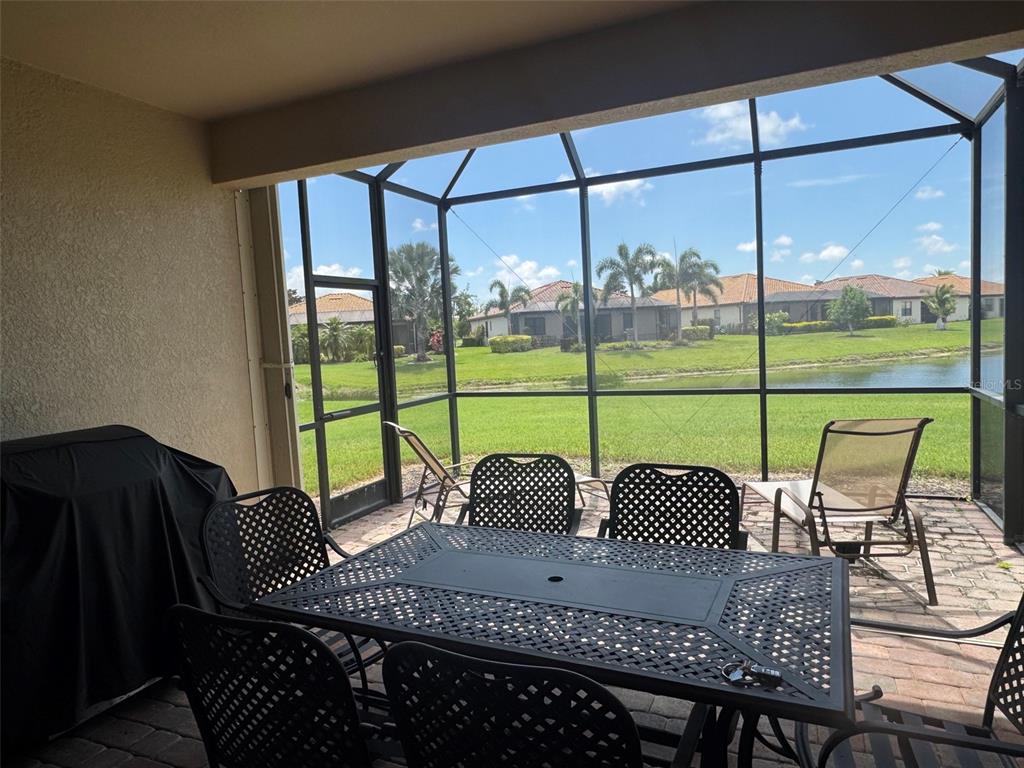 A covered patio with a screened enclosure overlooks a grassy lawn and a small pond — 218 WHISPERING PALMS LANE, BRADENTON, FL