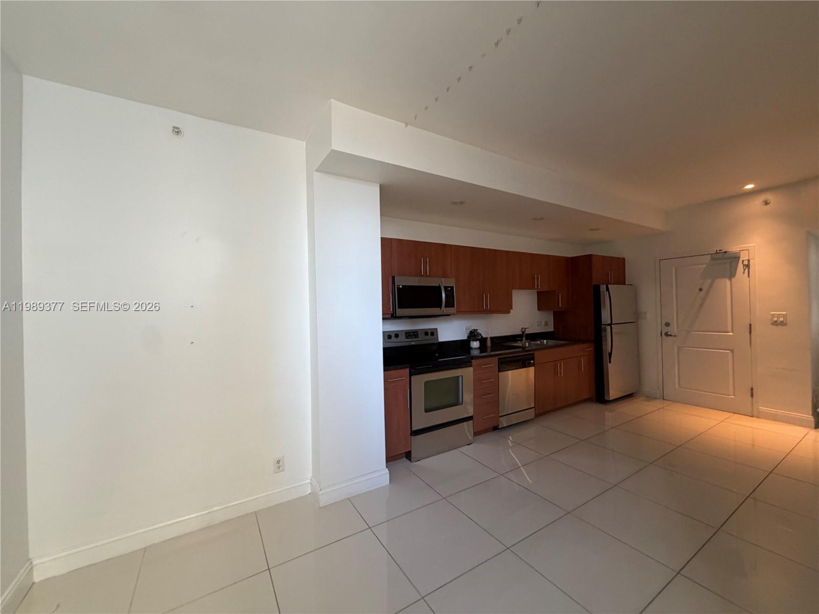 A kitchen with wood cabinets, stainless steel appliances, and white tile flooring — 111 E Flagler St # 606, Miami FL 33131, MIAMI, FL